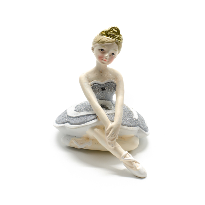 Ezüst csillogó tütüben kecsesen ülő és előre nyúló balerina